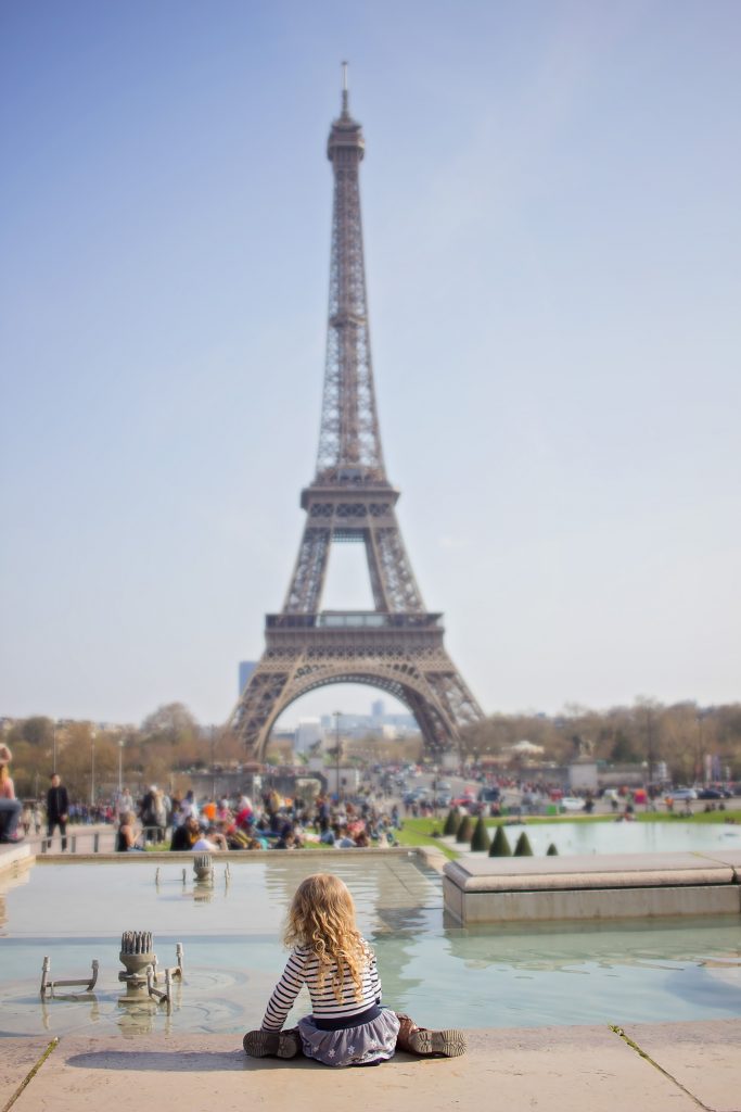 Girl sits in front of Eiffel Tower in Paris